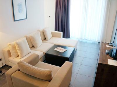 Sala de estar moderna con sofá claro, mesa de centro y ventana grande con cortinas.