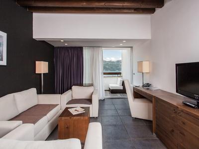 Sala de estar moderna con sofás blancos, muebles de madera y televisor de pantalla plana.