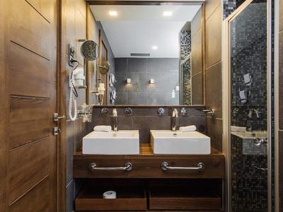 Interior de baño moderno con lavabo doble, detalles en madera y espejo iluminado.