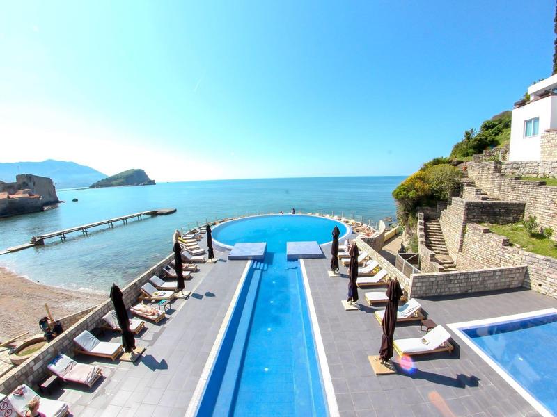Piscina al aire libre de lujo con vista al mar y terraza en un resort hotelero en la playa.