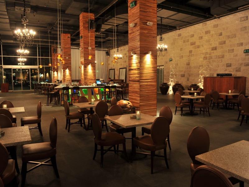 Acogedor comedor con mesas y sillas de madera, iluminación cálida y diseño rústico.