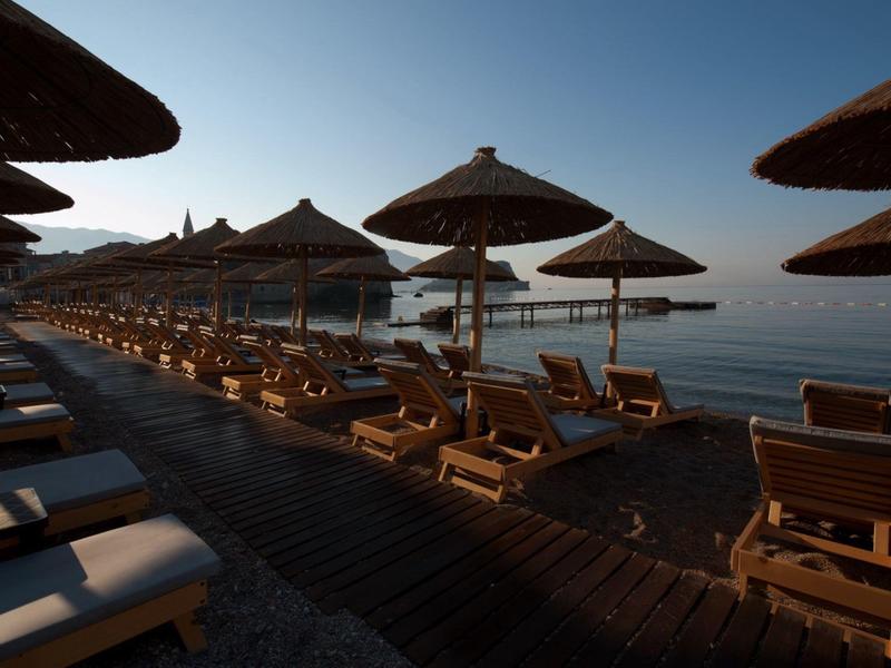 Camastros de madera vacíos y sombrillas en una playa tranquila al amanecer o al atardecer.