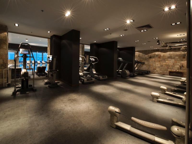 Gimnasio con equipos de entrenamiento y luz tenue en un hotel.