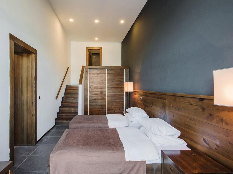 Habitación de hotel moderna con dos camas, elementos de madera e iluminación indirecta en las escaleras.