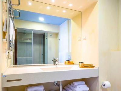 Baño moderno con gran espejo y estantes debajo con toallas blancas.