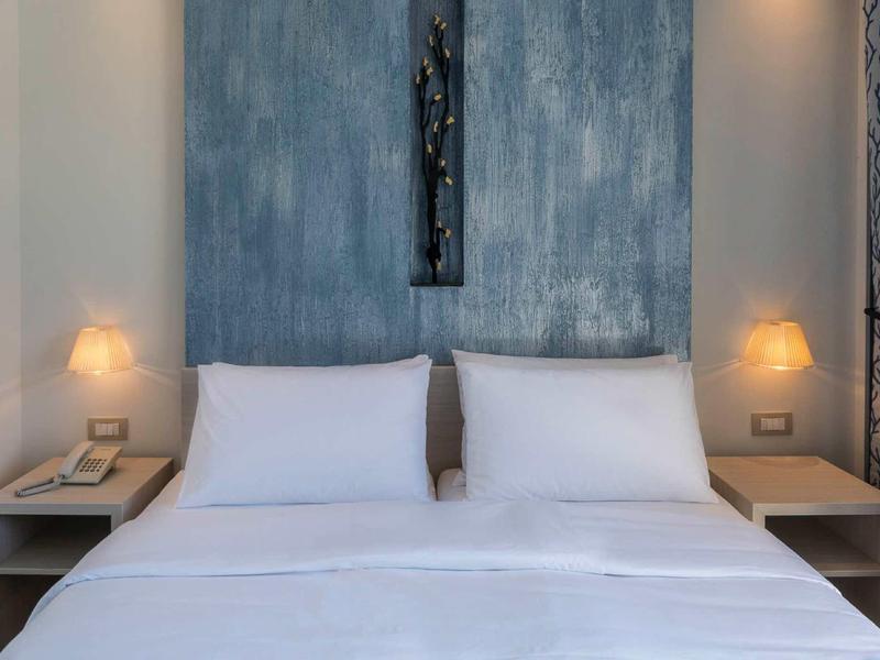 Habitación de hotel moderna con cama doble, ropa de cama blanca y decoración de pared elegante.