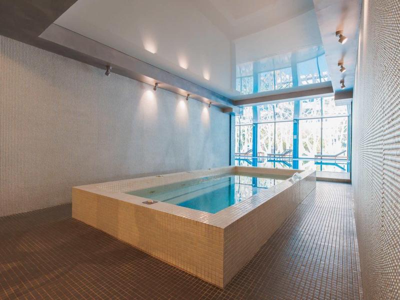 Pequeña piscina cubierta con grandes ventanas y focos en el techo de un hotel.