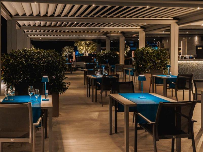 Ambiente elegante de restaurante con manteles azules, sillas y iluminación tenue para noches inolvidables.