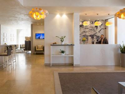 Lichte hotelreceptie met witte balie, moderne verlichting en zitplaatsen.