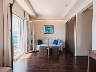 Lichte woonkamer met open balkon, bank, poefen en moderne houten vloer.