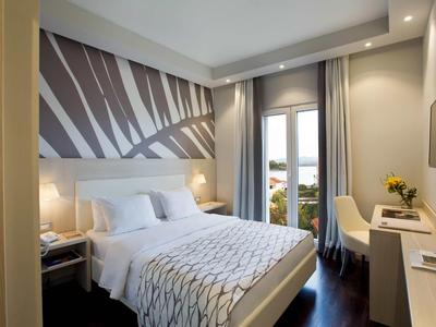 Modernes Hotelzimmer mit Doppelbett, Schreibtisch und Fenster mit Blick ins Freie.