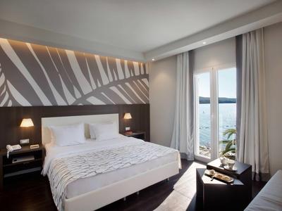 Moderne hotelkamer met groot bed, nachtkastjes en balkon met uitzicht op zee.