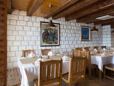 Interieur van een restaurant met houten stoelen, witte tafelkleden en kunst aan de muren.