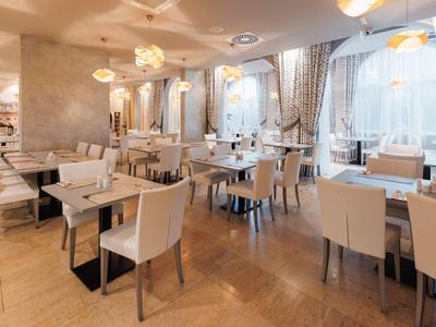 Licht, modern hotelrestaurant met witte stoelen en grote ramen.