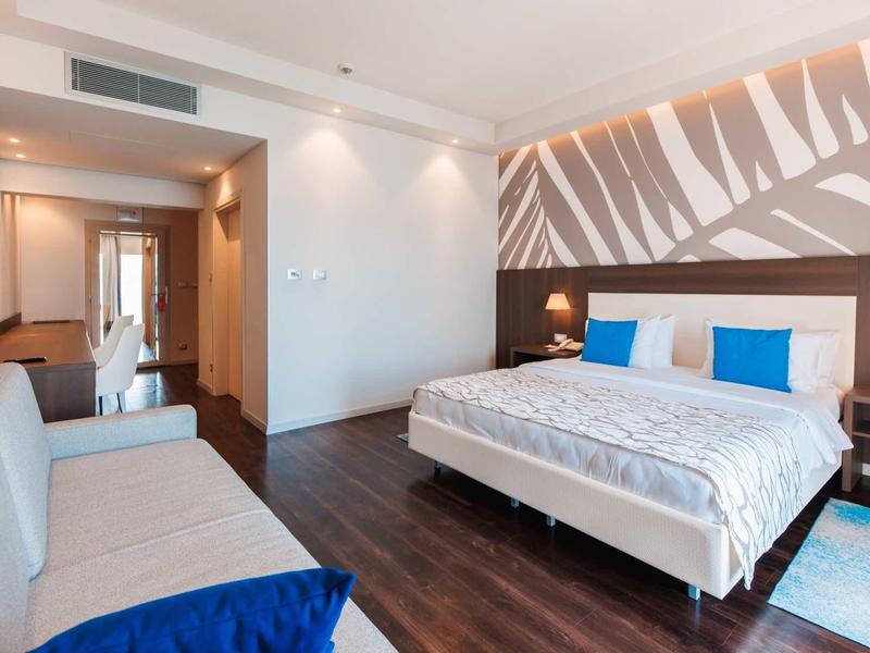 Moderne hotelkamer met tweepersoonsbed, bank en stijlvolle wanddecoratie.