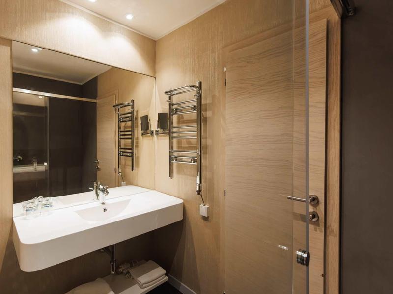 Moderne hotelbadkamer met grote witte wastafel en verwarmde handdoekhouder.