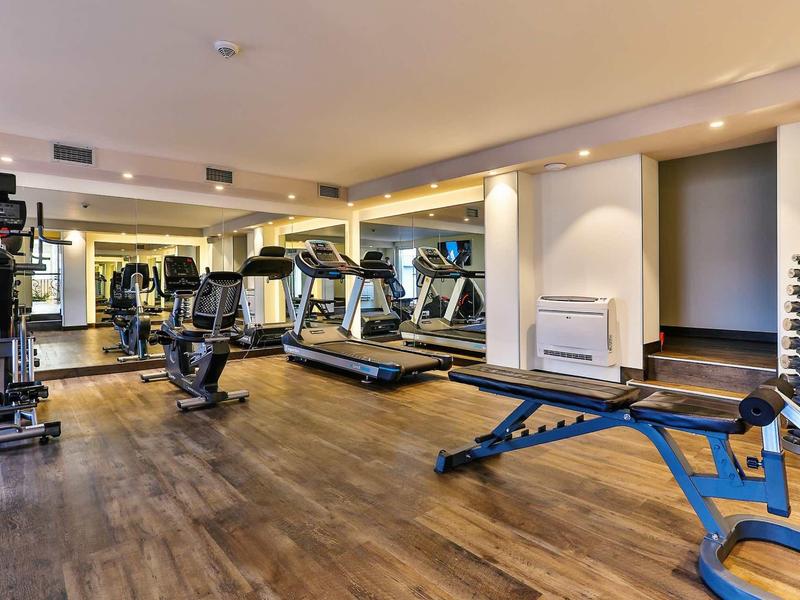 Moderne fitnessruimte met loopbanden, halters en fitnessapparatuur in een hotel.