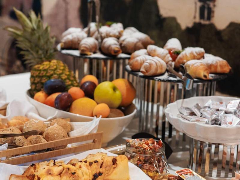 Buffet met fruit, gebak en snoep buiten voor een gebouw.