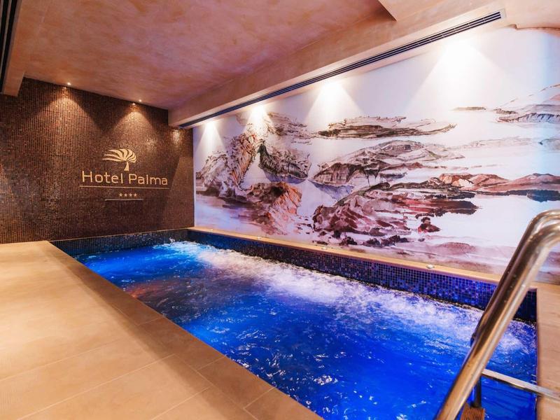 Overdekt zwembad met blauw verlicht water en decoratieve muurschildering in een hotel.