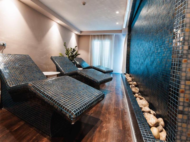 Moderne ontspanningsruimte met blauwe ligstoelen en wandfontein in een hotelspa