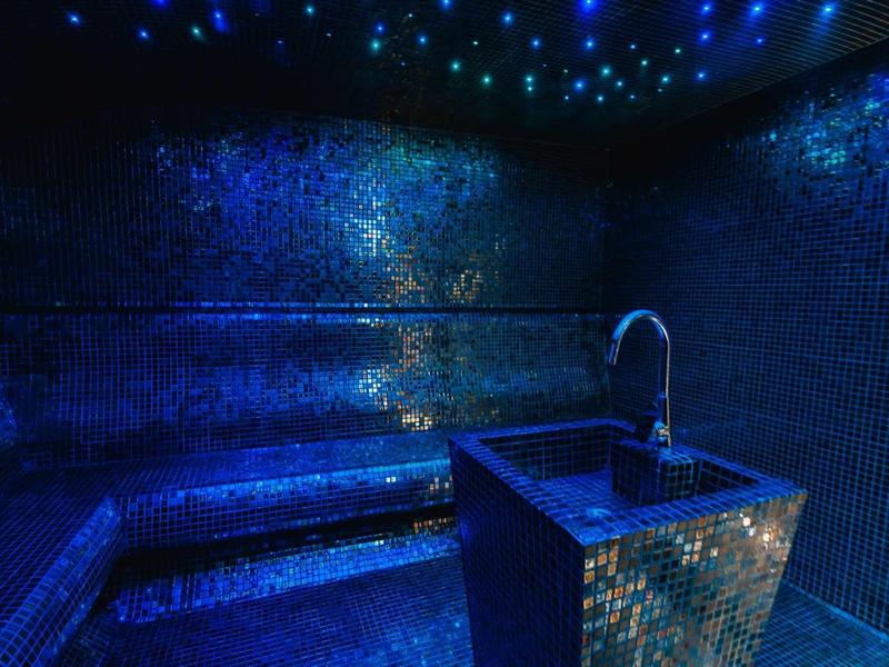 Luxe stoomkamer met blauwe mozaïektegels en stervormige plafondverlichting.