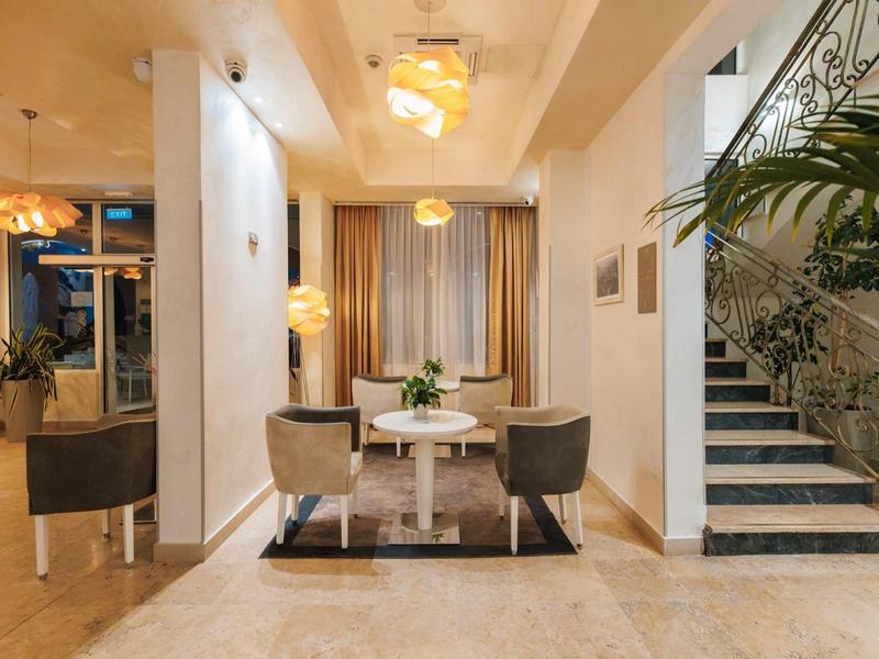 Elegante hotellobby met moderne zithoek en sierlijke trap.