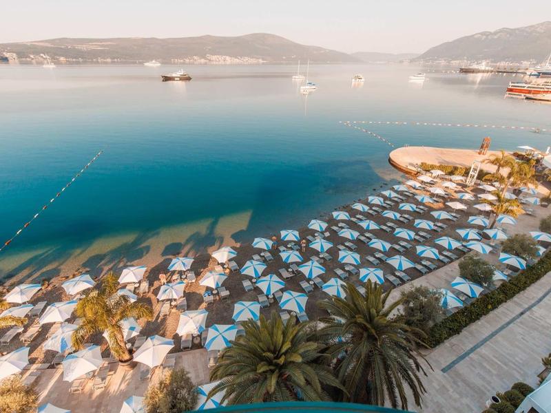 Strand met parasols en ligstoelen langs een rustige baai met helder water bij zonsopgang.
