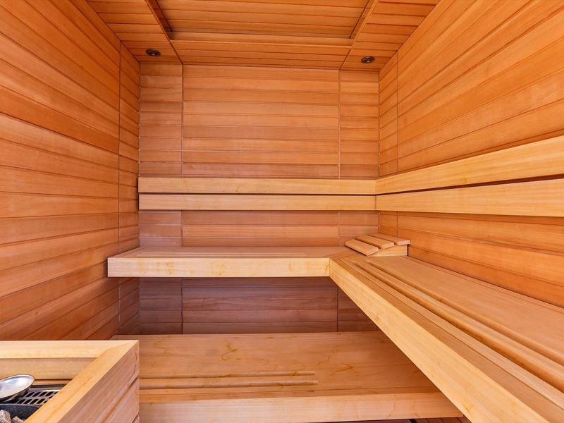Interior of a sauna with wooden benches and walls in warm lighting.