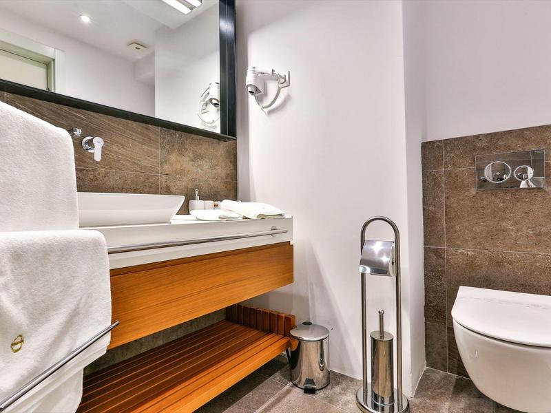 Modern bathroom with wall-mounted toilet, sink, and white towels.
