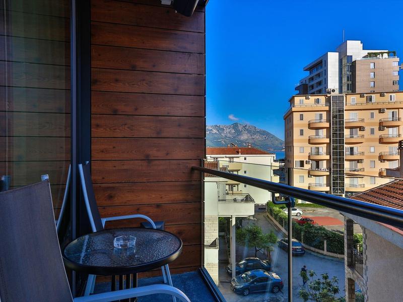 Balcony with chairs and table overlooking residential buildings and sky.