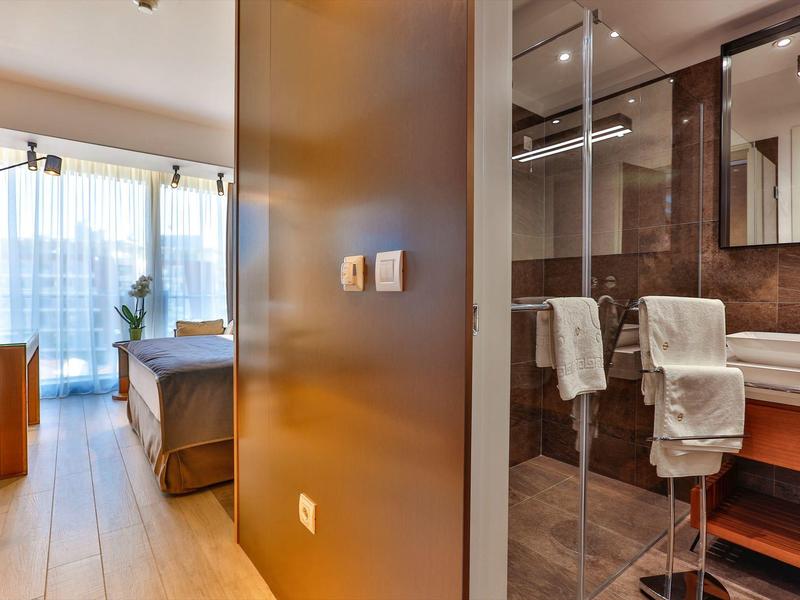 Modern hotel room area with bedroom and bathroom separated by a wall.