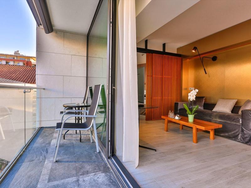 Balcony with chairs and modern living room area with sofa and wooden table.
