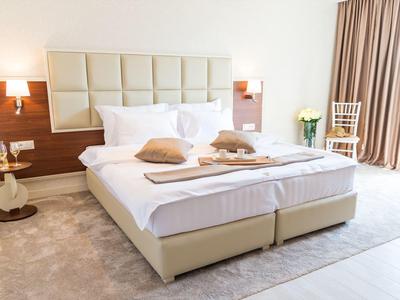 Bright hotel room with spacious double bed, wood accents, and daylight from curtains.