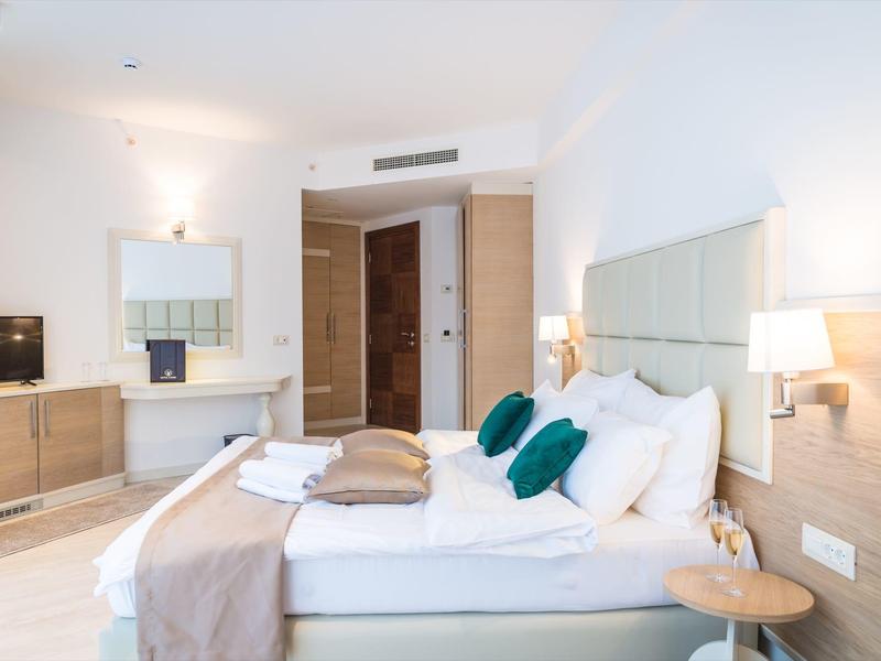 Bright hotel room with double bed, stylish lighting, and modern furnishings.