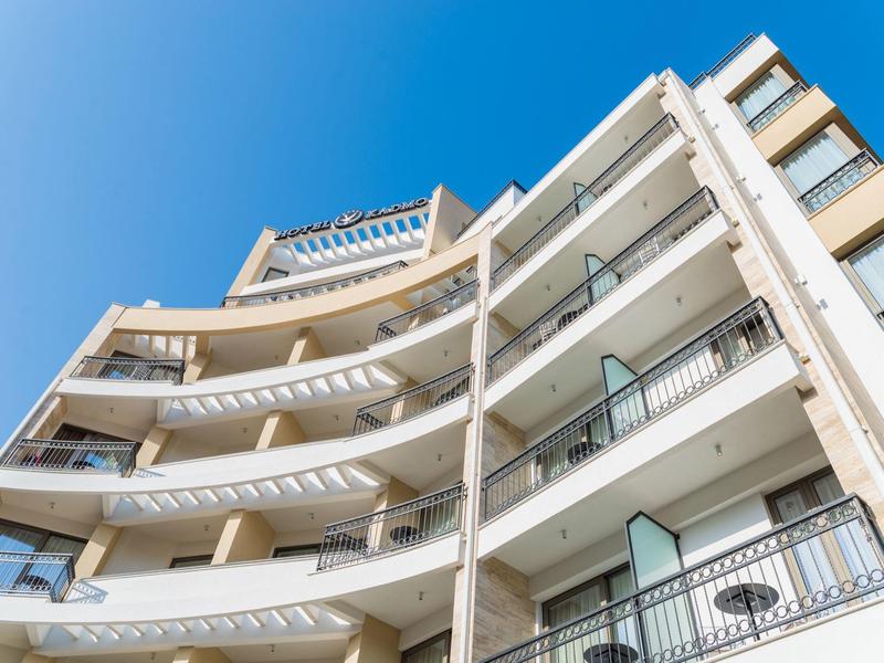 Modern hotel complex with balconies under a clear blue sky.
