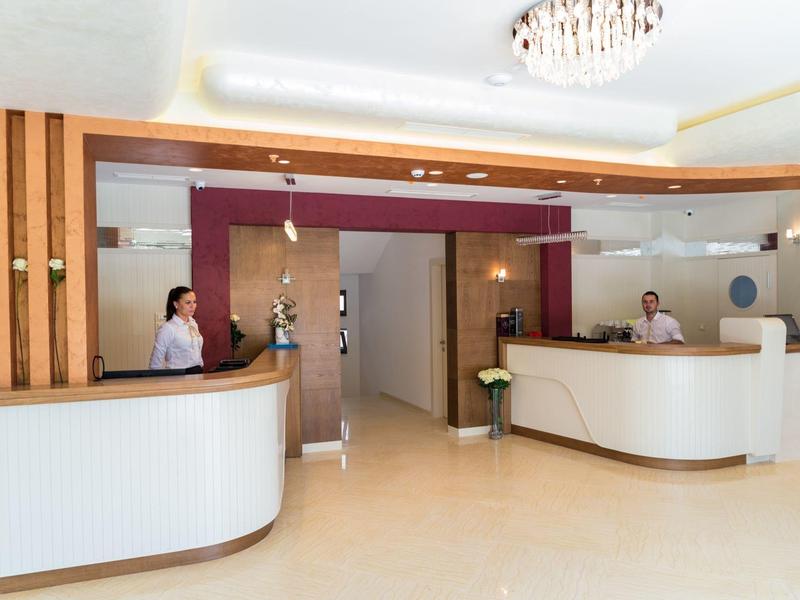 Bright hotel lobby with two modern reception desks and staff behind the counters.