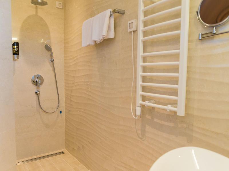 Modern bathroom with walk-in shower, towel rack, and sink.