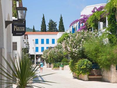 Un camino adoquinado soleado con plantas y edificios, ideal para unas vacaciones relajantes.