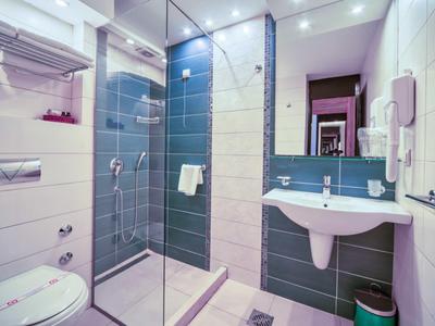 Baño moderno con ducha, inodoro y lavabo en diseño claro y limpio.