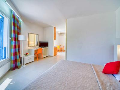 Habitación de hotel luminosa con cama, escritorio, TV y ventana con cortinas coloridas.