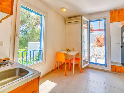 Área de cocina y comedor luminosa con ventana, puerta al balcón y mobiliario sencillo.