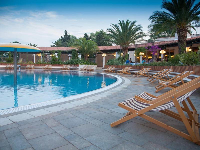 Piscina al aire libre con sillas reclinables y palmeras en un hotel