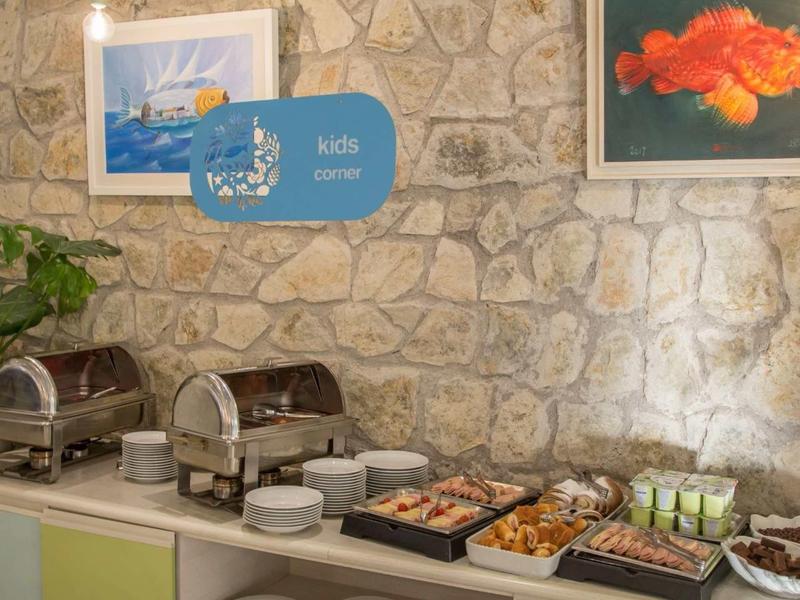 Buffet con comida variada en un mostrador frente a una pared de piedra en un hotel.