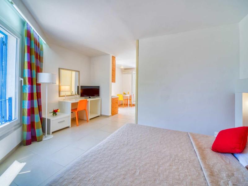 Habitación de hotel luminosa con cama, escritorio, TV y ventana con cortinas coloridas.