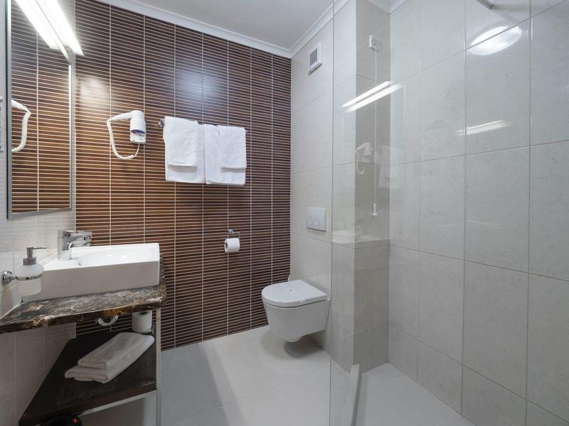 Bagno moderno con piastrelle marroni e bianche, lavabo, WC e asciugamani.