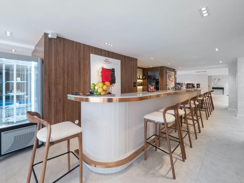 Bar dell'hotel moderno con accenti in legno e sgabelli alti in una stanza luminosa.