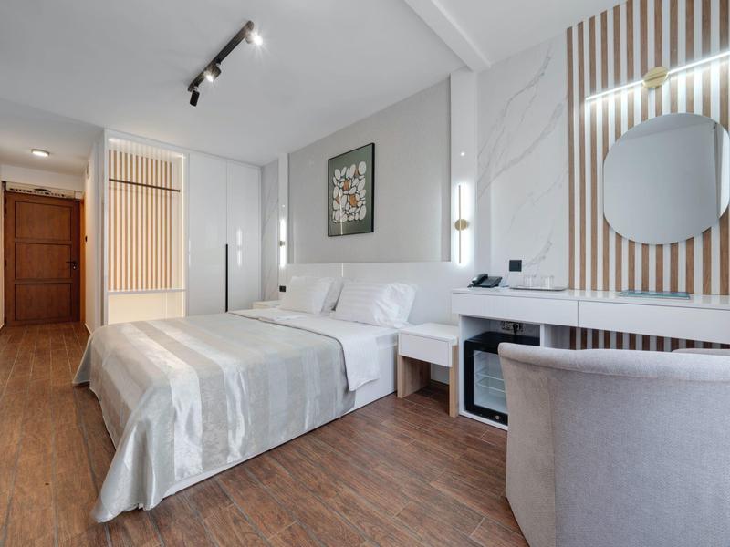 Camera d'hotel moderna con letto matrimoniale, scrivania, sedia e pavimento in legno caldo.