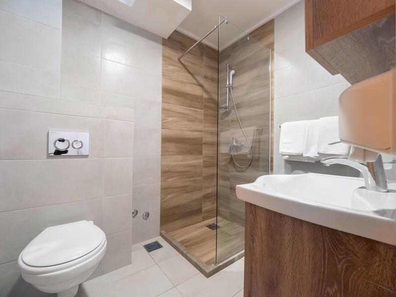 Bagno moderno con WC, doccia in vetro e mobile lavabo effetto legno.