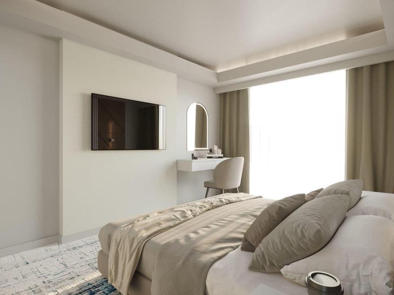 Camera d'hotel moderna con letto, TV a muro e scrivania accanto alla finestra.