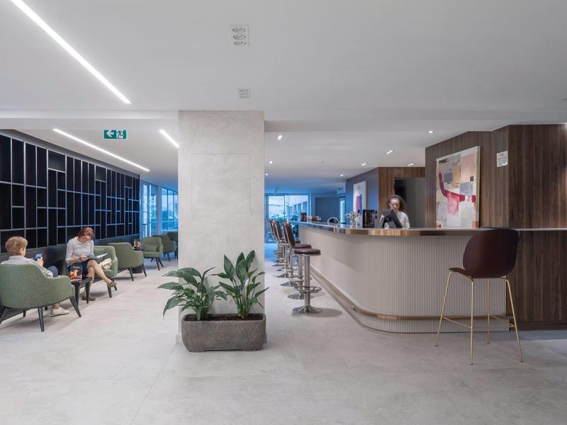 Moderna hall dell'hotel con elegante reception e area salotto con ospiti.